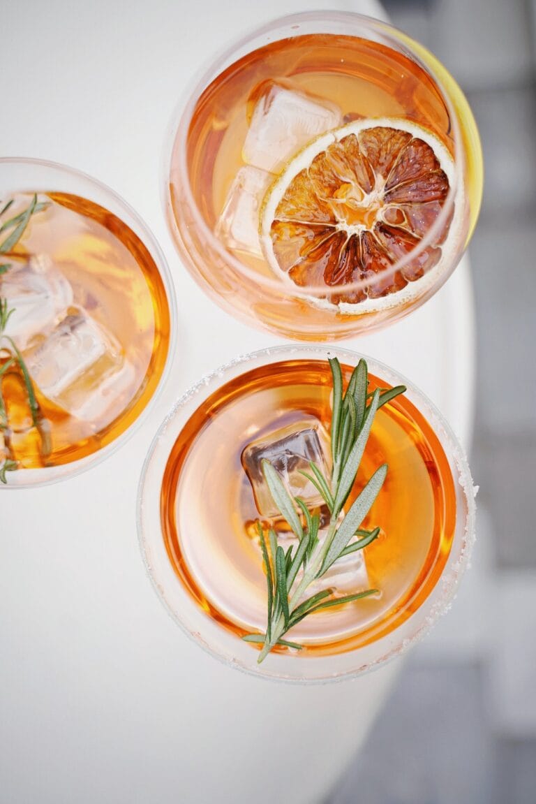 3 cocktails de couleurs oranges avec des assortiments de fruits et de plantes