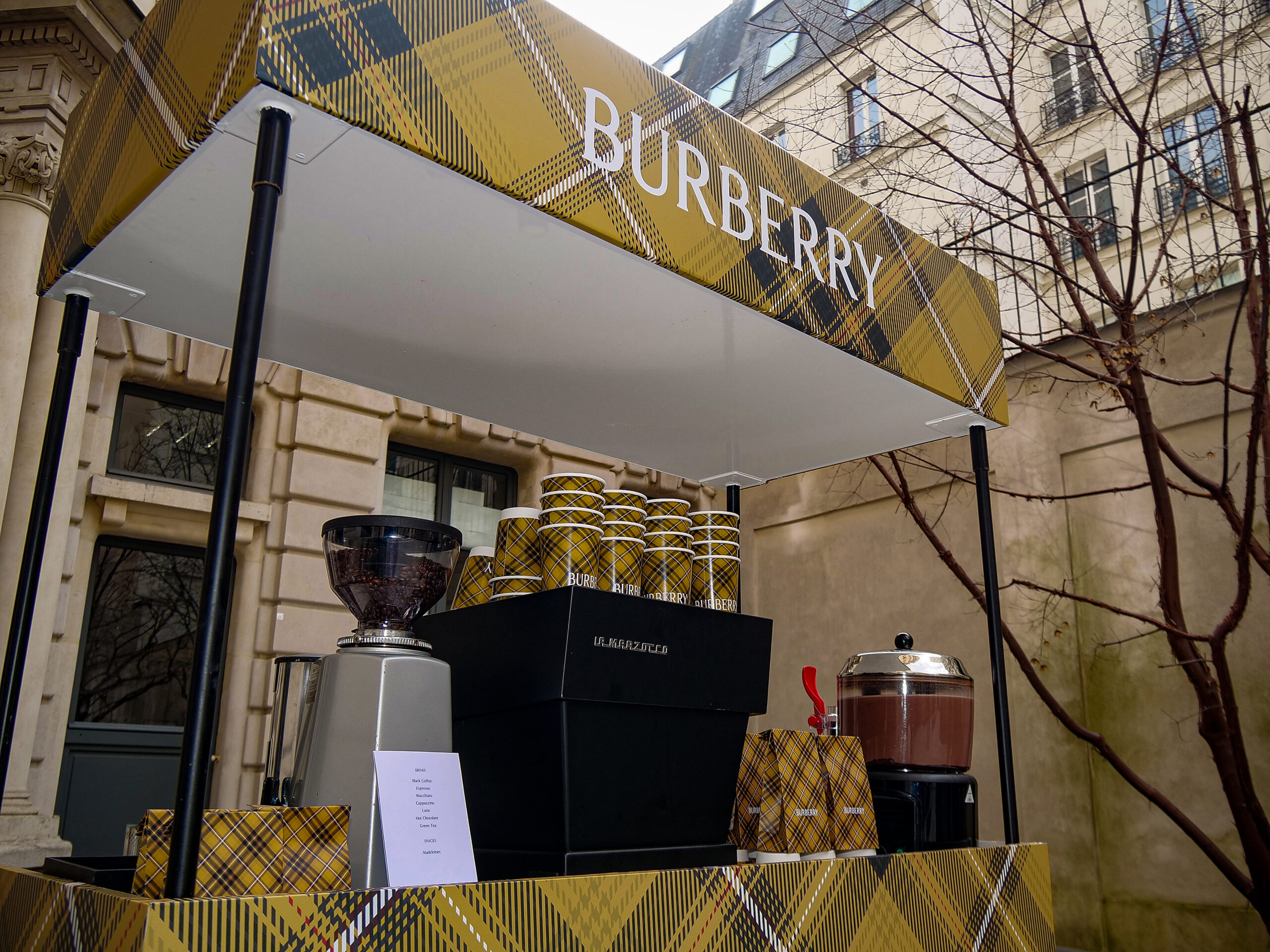 Barista événementiel professionnel préparant des cafés sur un kiosque personnalisé lors d'un événement d'entreprise.