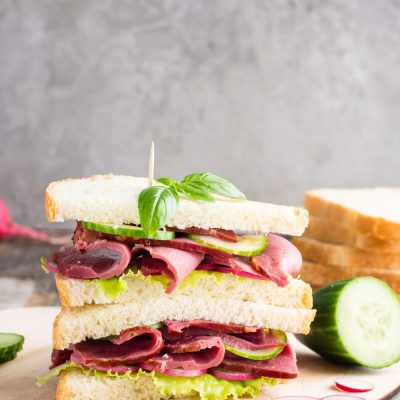 double-sandwich-with-pastrami-cucumber-radish-basil-cutting-board-american-snack-rustic-style